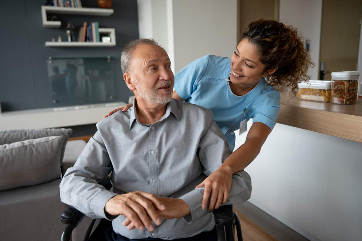 Portrait of a Latin American senior man in a wheelchair talking to his home caregiver - medical concepts